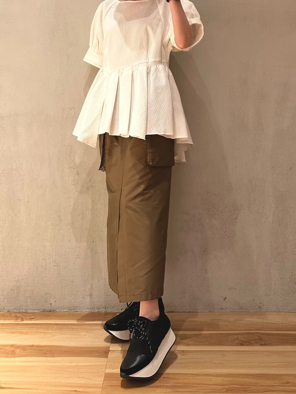 ブラウン系のスカート、ブラック系のスニーカー、ホワイト系のシャツ/ブラウスを着用したレディースの春コーディネートの2枚目の写真