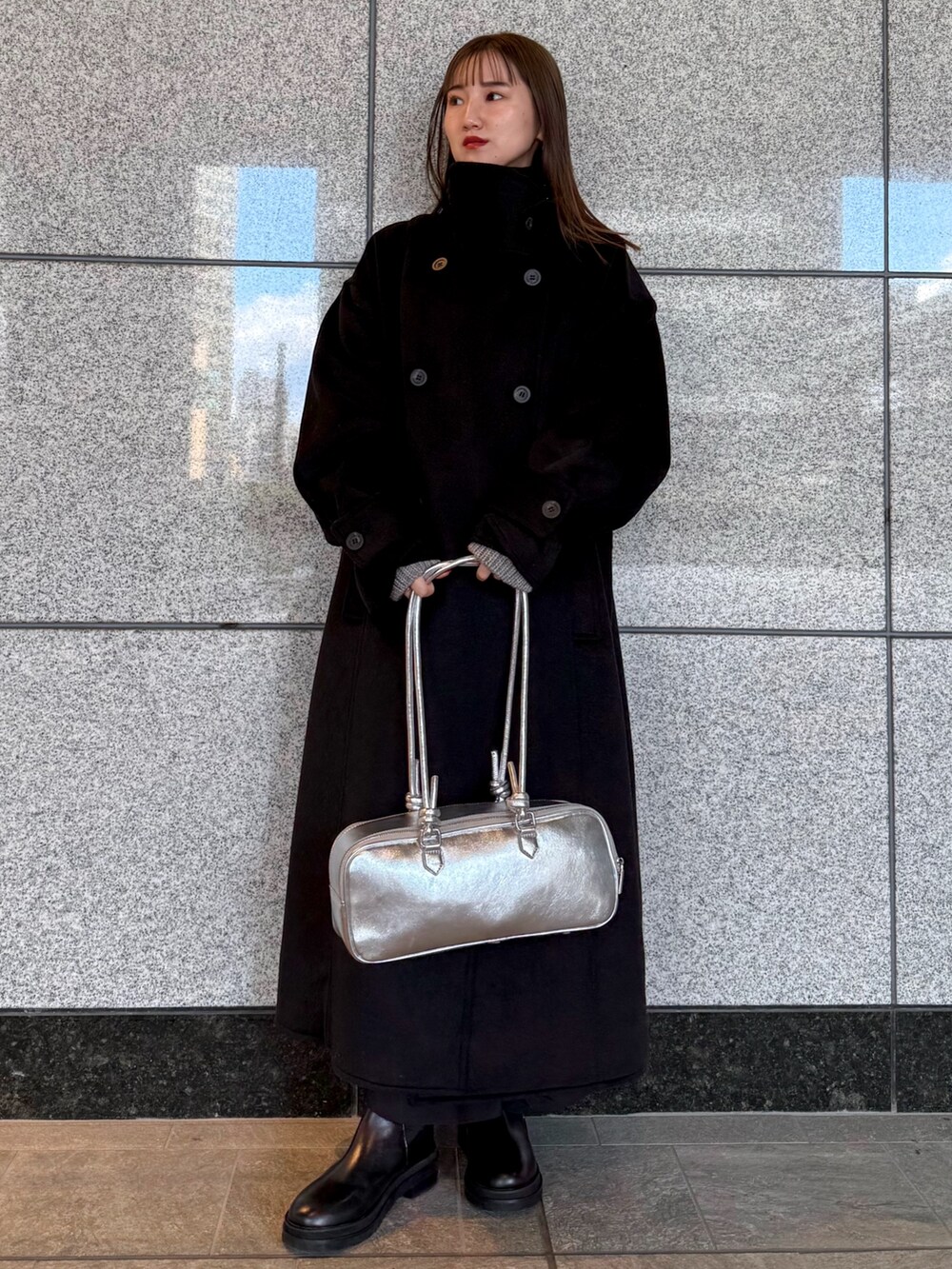 ブラック系のその他アウター、シルバー系のボストンバッグ、ブラック系のブーツを着用したレディースの冬コーディネートの2枚目の写真