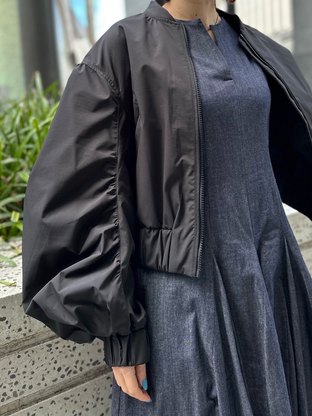 ホワイト系のスニーカー、ブルー系のワンピース、ブラック系のブルゾンを着用したレディースの春コーディネートの3枚目の写真