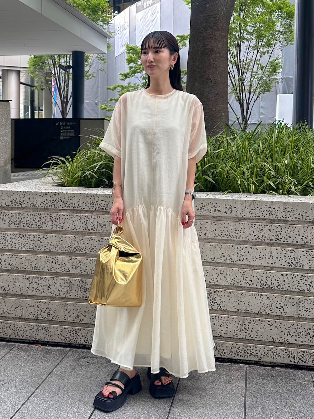 ブラック系のキャミソール、ゴールド系のハンドバッグ、ブラック系のサンダルを着用したレディースの夏コーディネートの2枚目の写真