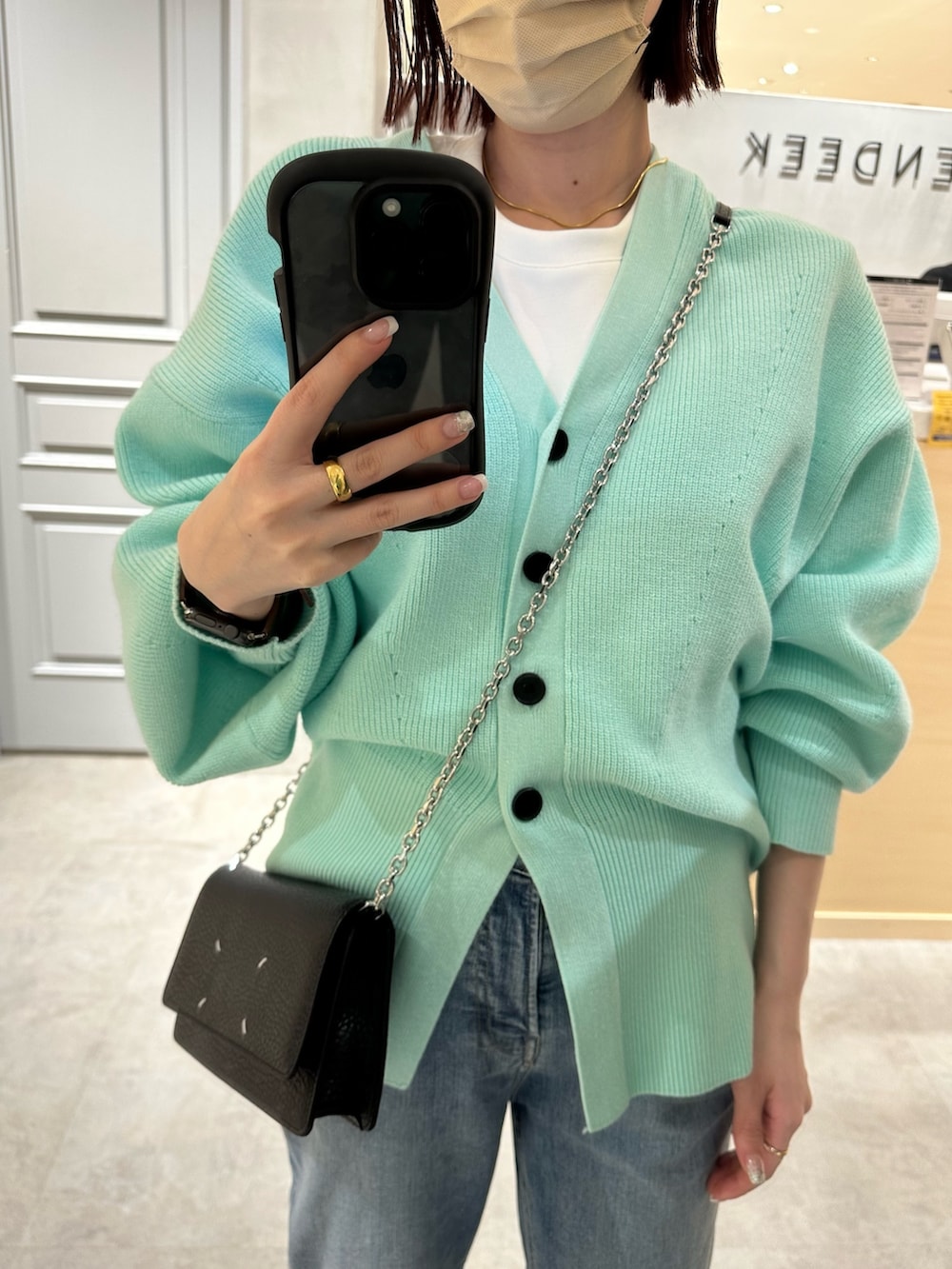 ブルー系のデニムパンツ、グリーン系のカーディガン/ボレロ、ホワイト系のTシャツ/カットソーを着用したレディースの冬コーディネートの5枚目の写真