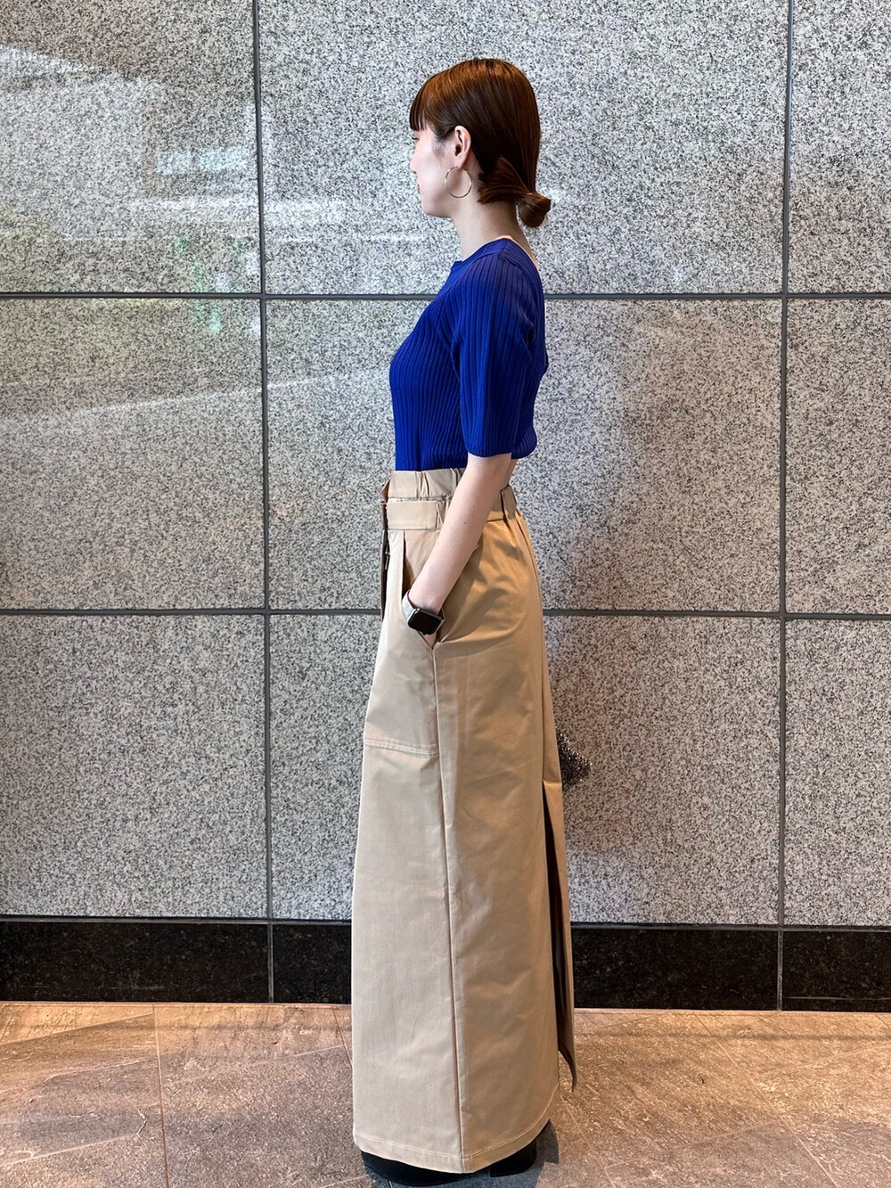 ブルー系のニット/セーター、ブラック系のノーカラージャケット、ベージュ系のスカートを着用したレディースの秋コーディネートの7枚目の写真