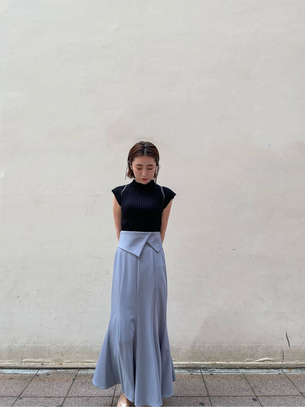 ブルー系のスカート、ブラック系のニット/セーターを着用したレディースの夏コーディネートの3枚目の写真