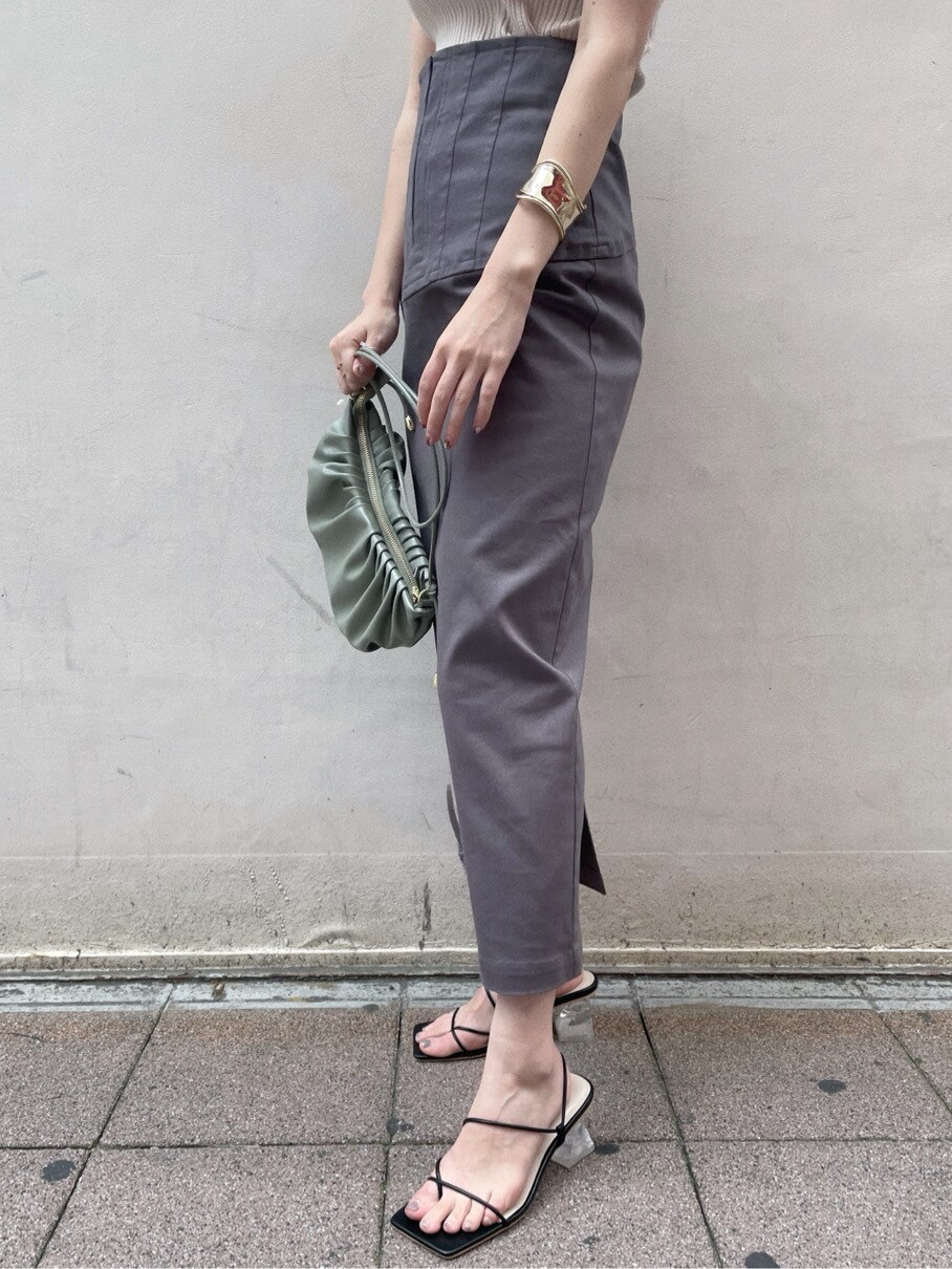 グリーン系のハンドバッグ、グレー系のスカート、ブラック系のサンダルを着用したレディースの春コーディネートの4枚目の写真