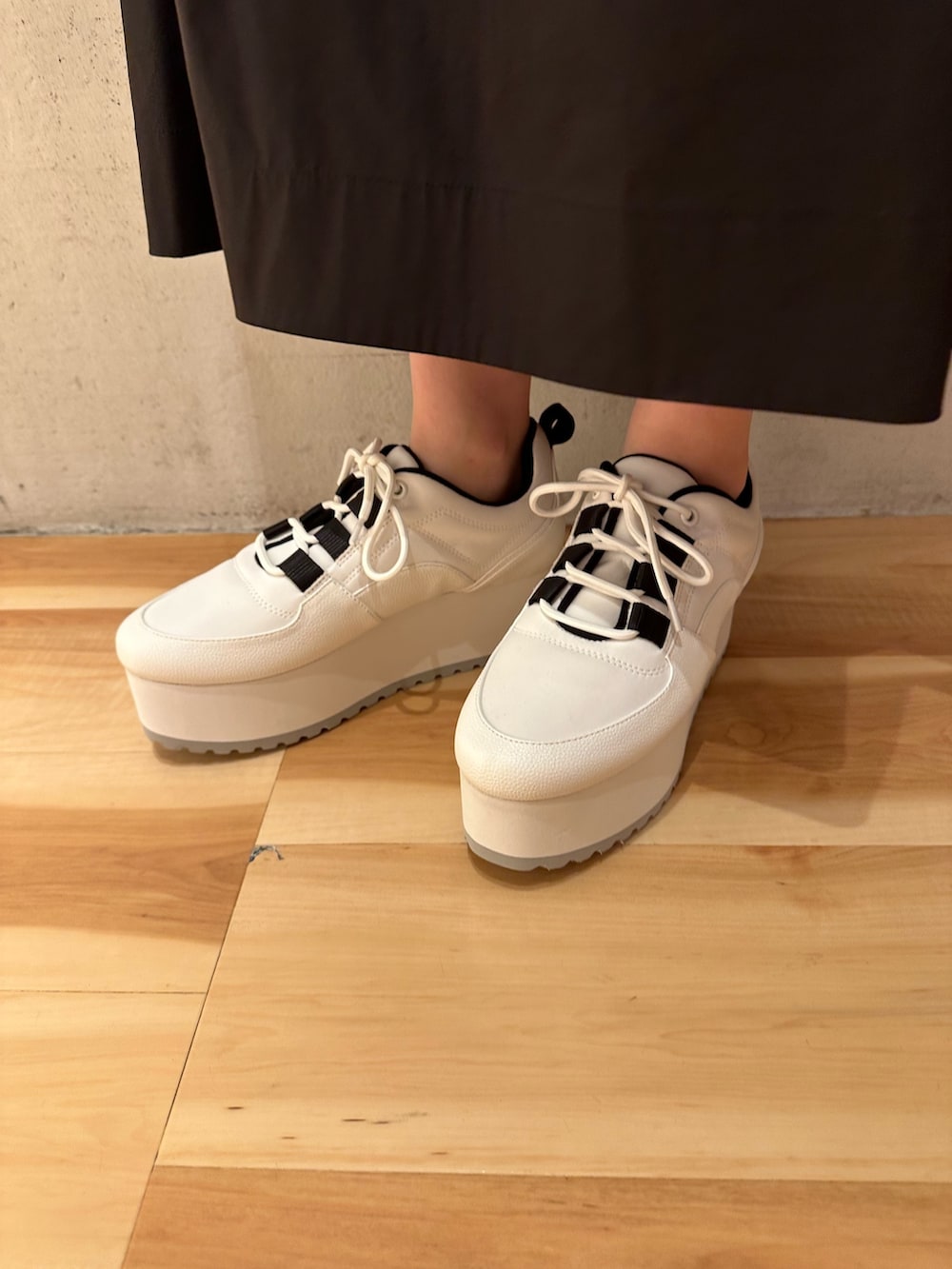 ブラック系のワンピース、ホワイト系のスニーカー、ゴールド系のピアス（両耳用）を着用したレディースの夏コーディネートの7枚目の写真