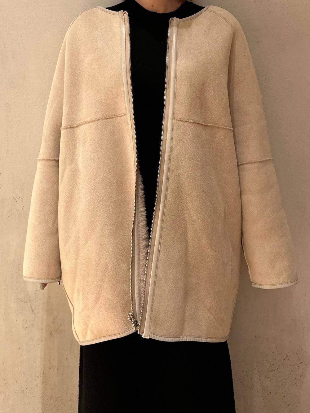 ブラック系のスカート、ブラック系のブーツ、ベージュ系のノーカラーコートを着用したレディースの夏コーディネートの7枚目の写真