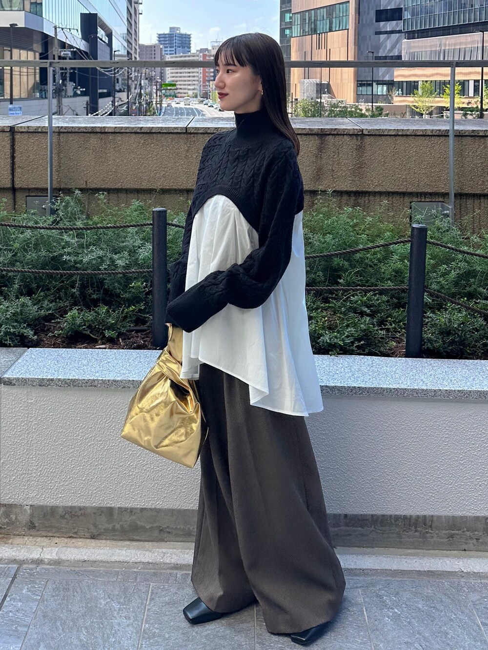 ブラック系のニット/セーター、ブラウン系のその他パンツ、ゴールド系のハンドバッグを着用したレディースの秋コーディネートの3枚目の写真