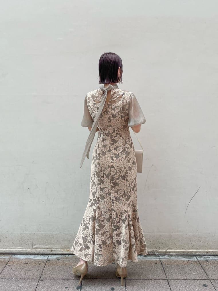 ベージュ系のドレス、ゴールド系のパンプス、ベージュ系のクラッチバッグを着用したレディースの夏コーディネートの4枚目の写真