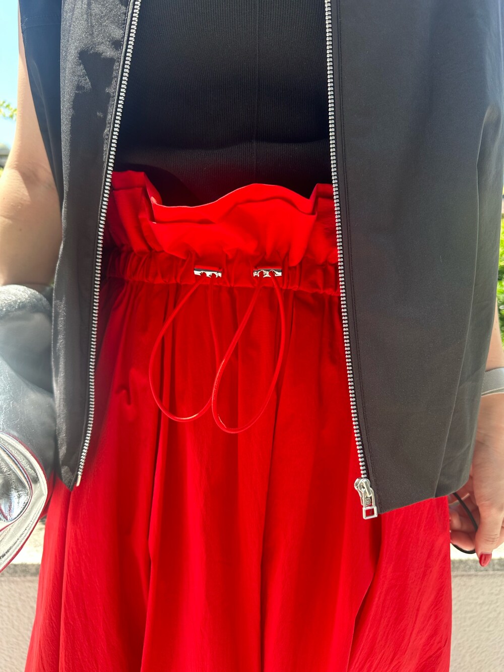 レッド系のスカート、シルバー系のトートバッグ、シルバー系のパンプスを着用したレディースの夏コーディネートの8枚目の写真