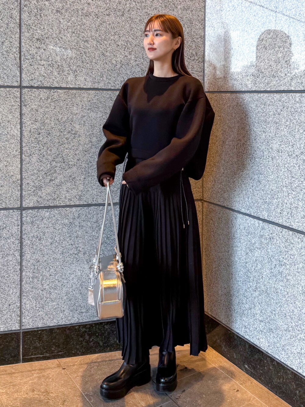 ブラック系のスウェット、シルバー系のボストンバッグ、ブラック系のワンピースを着用したレディースの冬コーディネートの2枚目の写真