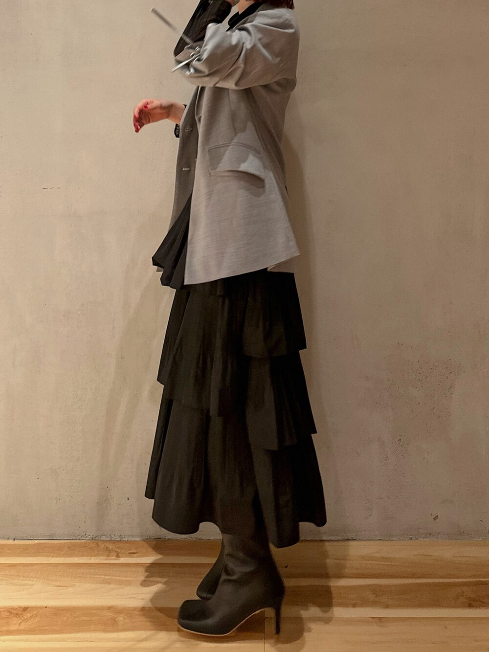 ブラック系のスカート、ブラック系のニット/セーター、グレー系のテーラードジャケットを着用したレディースの秋コーディネートの4枚目の写真