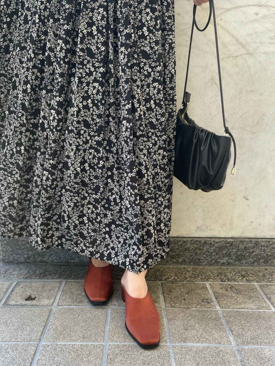 ブラック系のハンドバッグ、ブラック系のワンピース、オレンジ系のスリッポンを着用したレディースの夏コーディネートの6枚目の写真