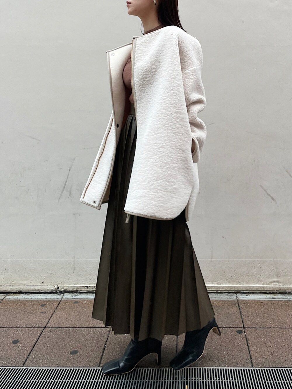 ブラウン系のスカート、ホワイト系のムートンコート、ベージュ系のニット/セーターを着用したレディースの冬コーディネートの5枚目の写真