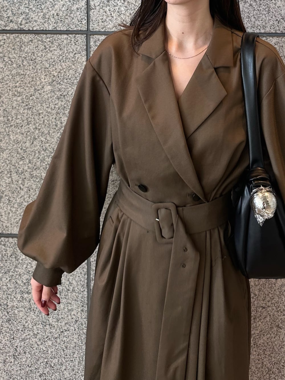 ブラウン系のワンピース、ゴールド系のブーツ、ブラック系のハンドバッグを着用したレディースの秋コーディネートの6枚目の写真