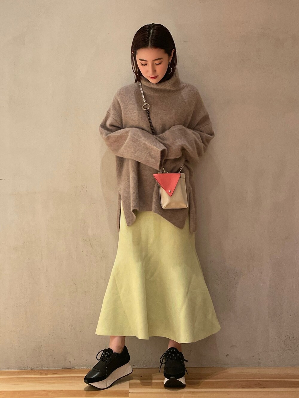 ベージュ系のショルダーバッグ、グリーン系のスカート、ブラック系のスニーカーを着用したレディースの秋コーディネートの2枚目の写真