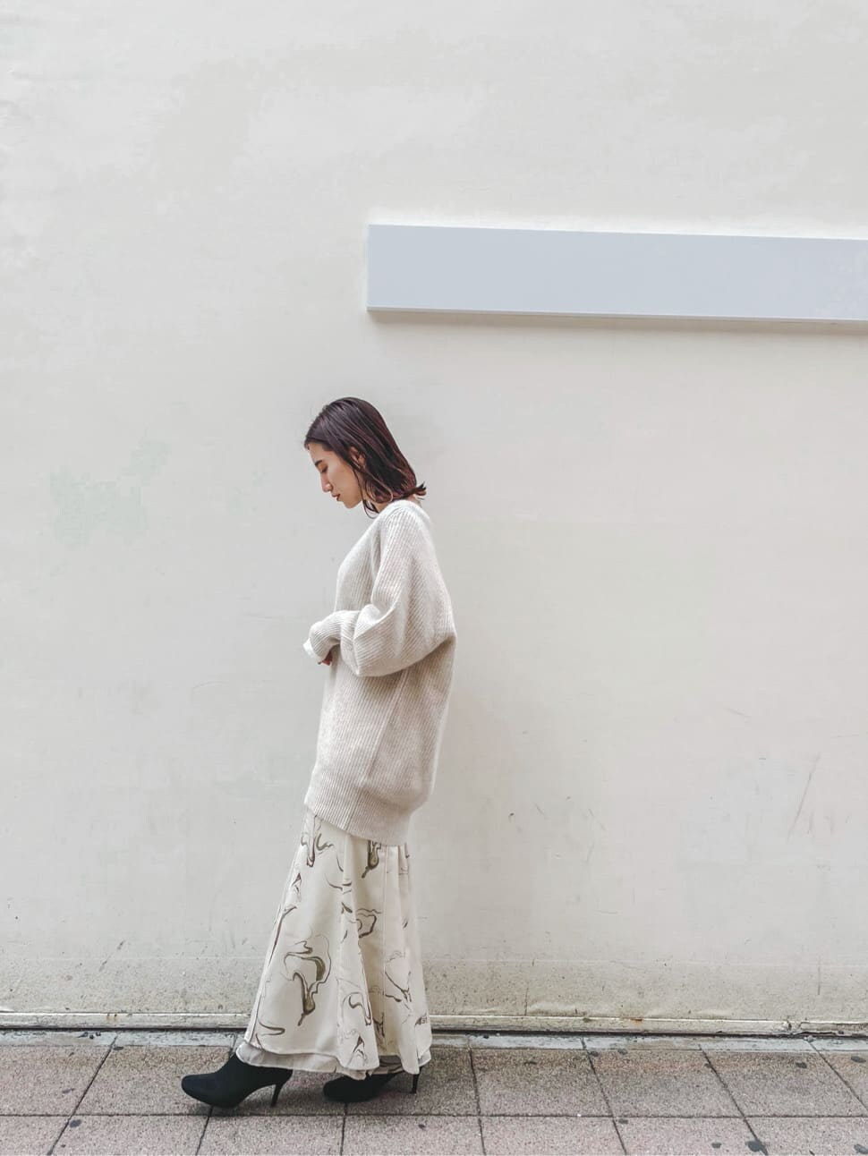 ホワイト系のスカート、ホワイト系のニット/セーター、ホワイト系のTシャツ/カットソーを着用したレディースの秋コーディネートの2枚目の写真
