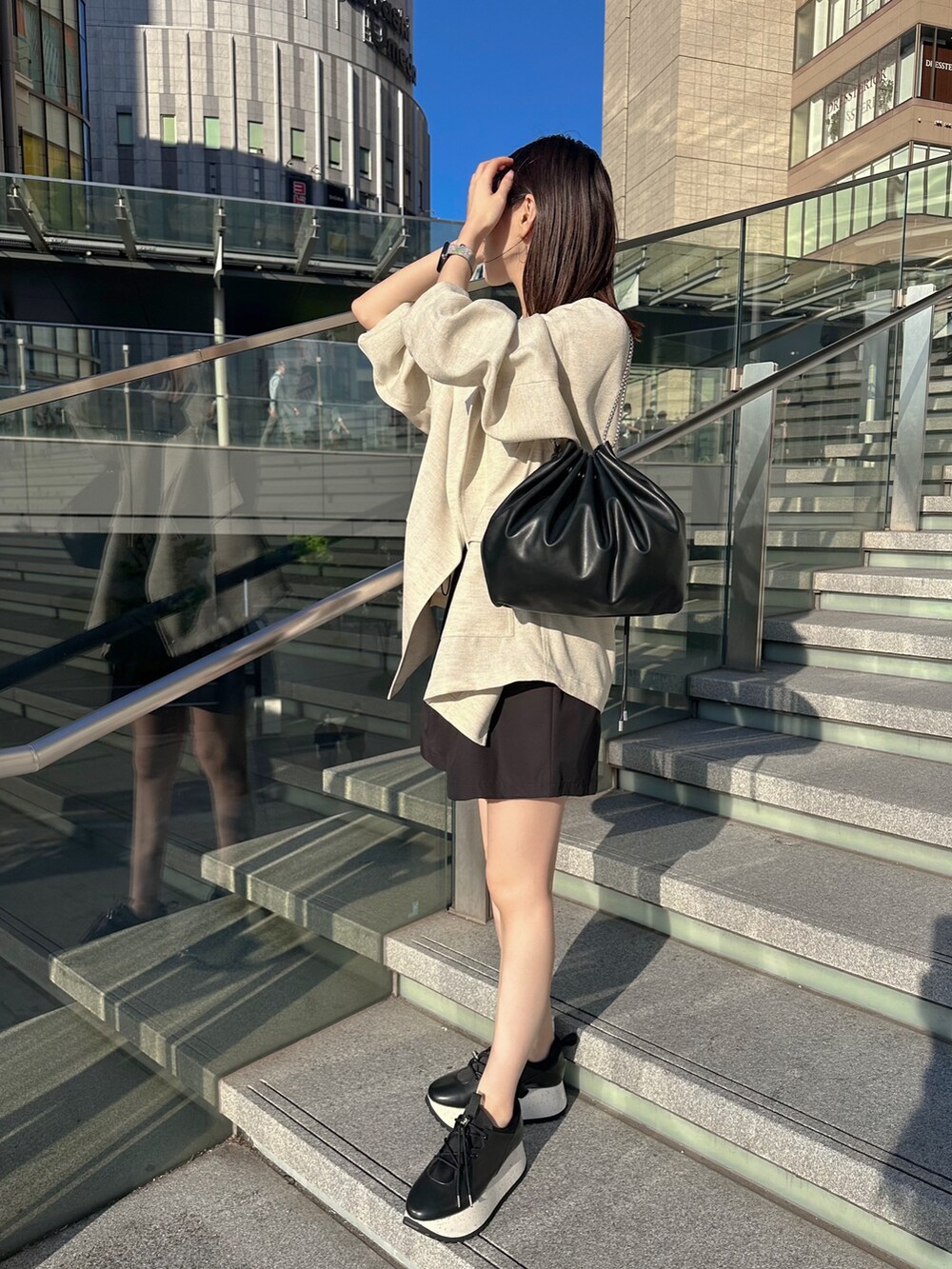 ブラック系のキャミソール、ベージュ系のテーラードジャケット、ブラック系のショルダーバッグを着用したレディースの春コーディネートの2枚目の写真
