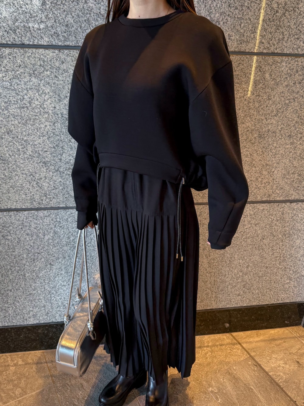 ブラック系のスウェット、シルバー系のボストンバッグ、ブラック系のワンピースを着用したレディースの冬コーディネートの4枚目の写真