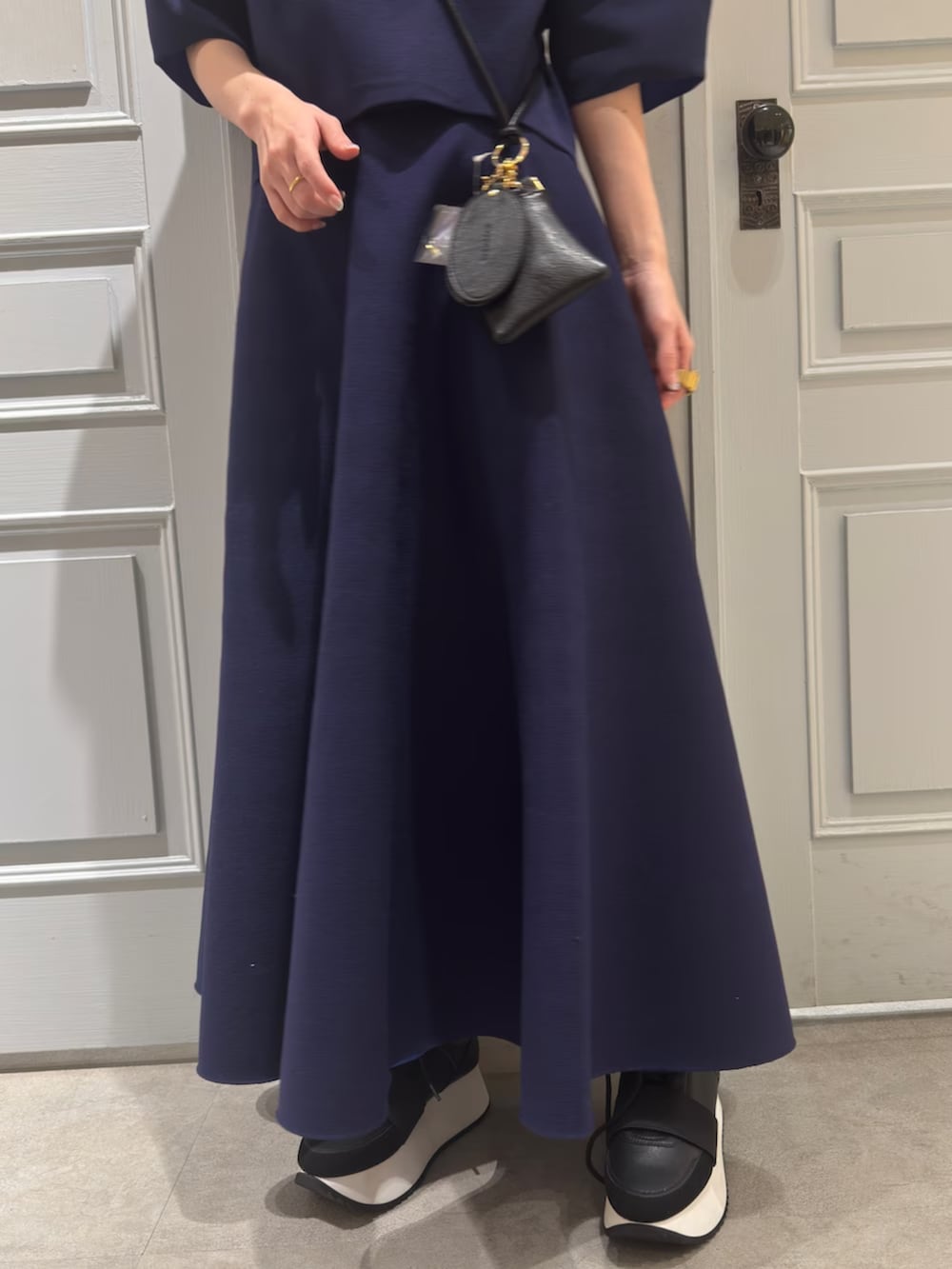 ブルー系のニット/セーター、ブルー系のスカート、ブラック系のスマホグッズを着用したレディースの春コーディネートの8枚目の写真