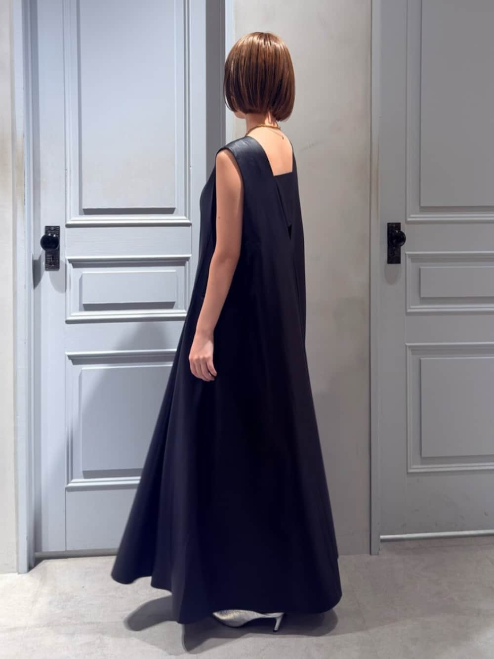 シルバー系のパンプス、ブラック系のワンピースを着用したレディースの春コーディネートの2枚目の写真