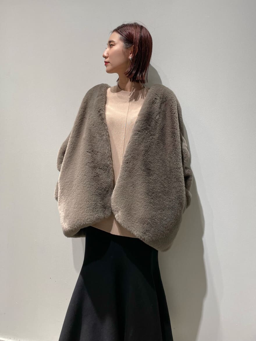 ブラウン系のノーカラーコート、ベージュ系のニット/セーター、ブラック系のブーツを着用したレディースの秋コーディネートの2枚目の写真