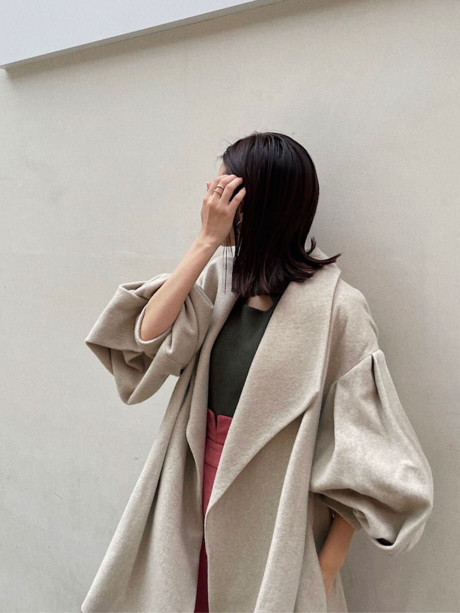 ブラック系のブーツ、ベージュ系のその他アウター、ピンク系のスカートを着用したレディースの秋コーディネートの2枚目の写真