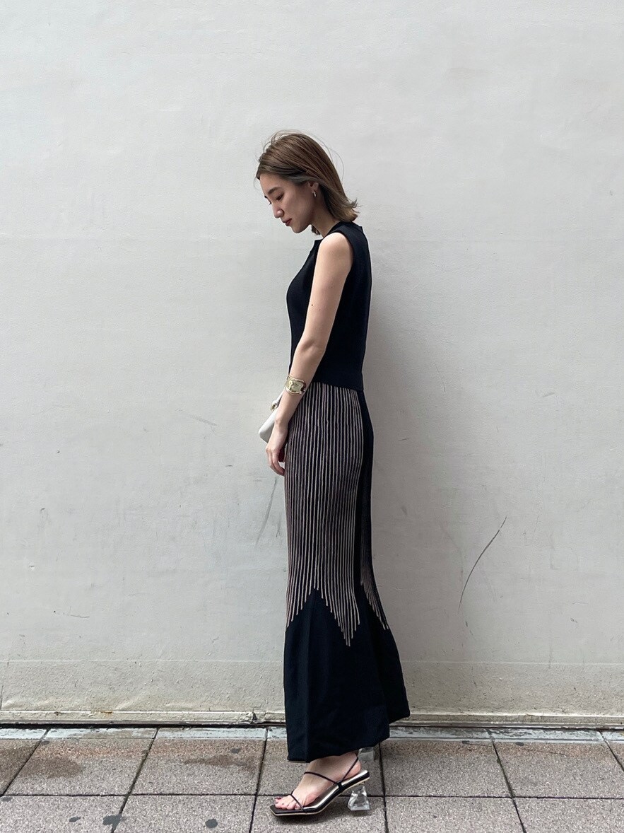 ホワイト系のショルダーバッグ、ブラック系のワンピース、ブラック系のサンダルを着用したレディースの春コーディネートの2枚目の写真