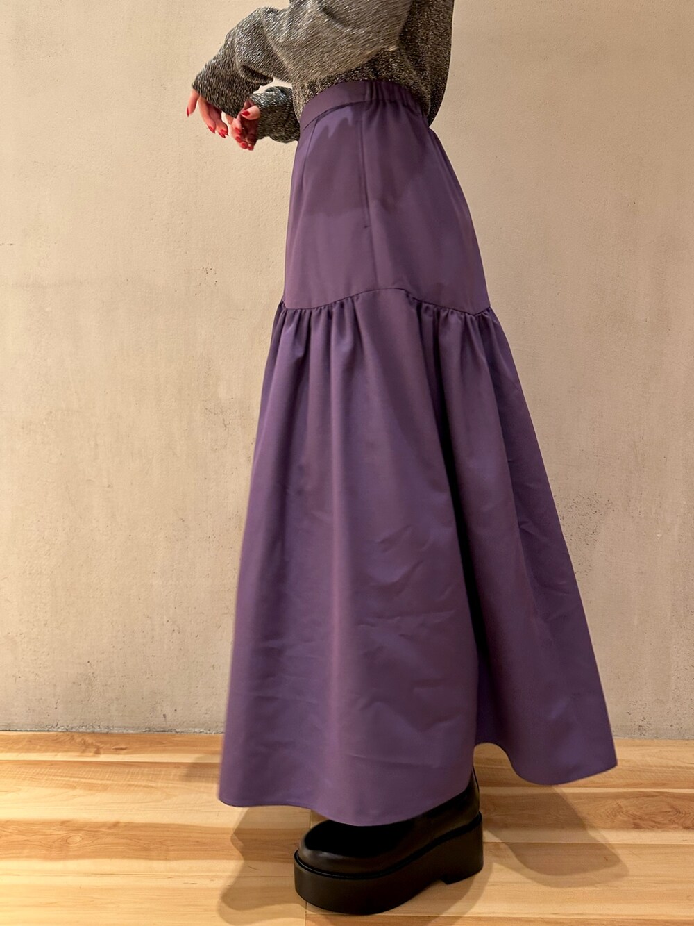 パープル系のスカート、ブラック系のノーカラーコート、シルバー系のTシャツ/カットソーを着用したレディースの秋コーディネートの6枚目の写真