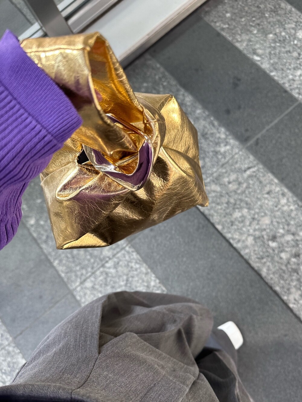 パープル系のニット/セーター、グレー系のその他パンツ、ゴールド系のハンドバッグを着用したレディースの春コーディネートの8枚目の写真