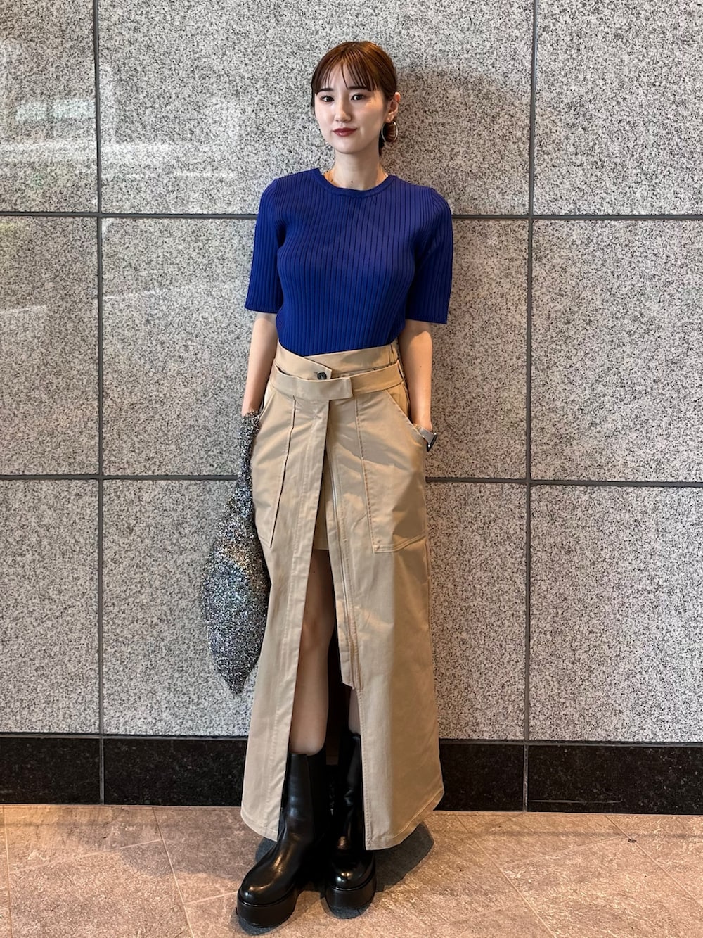 ブルー系のニット/セーター、ブラック系のノーカラージャケット、ベージュ系のスカートを着用したレディースの秋コーディネートの4枚目の写真