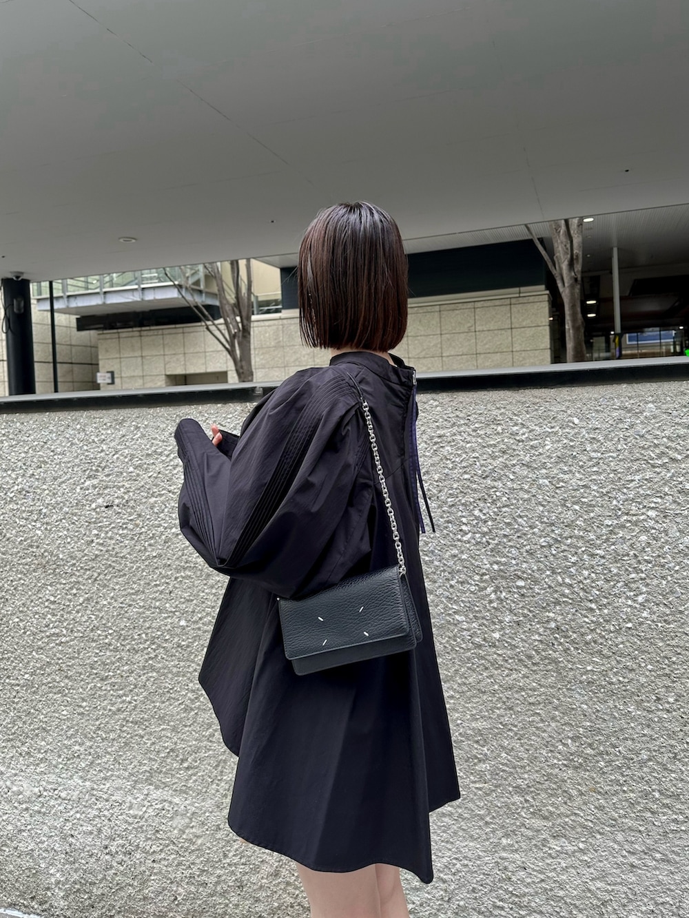 ブラック系のショルダーバッグ、ブラック系のシャツ/ブラウス、ブラック系のスニーカーを着用したレディースの冬コーディネートの2枚目の写真