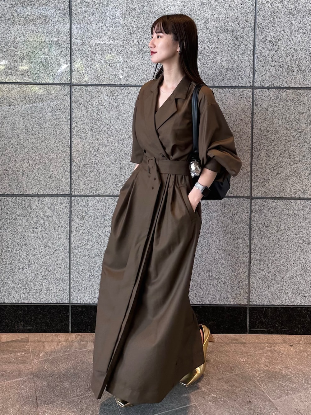 ブラウン系のワンピース、ゴールド系のブーツ、ブラック系のハンドバッグを着用したレディースの秋コーディネートの2枚目の写真