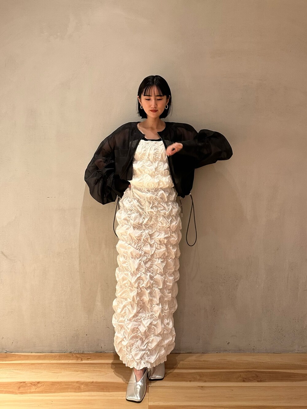 ホワイト系のワンピース、シルバー系のパンプス、ブラック系のブルゾンを着用したレディースの冬コーディネートの5枚目の写真