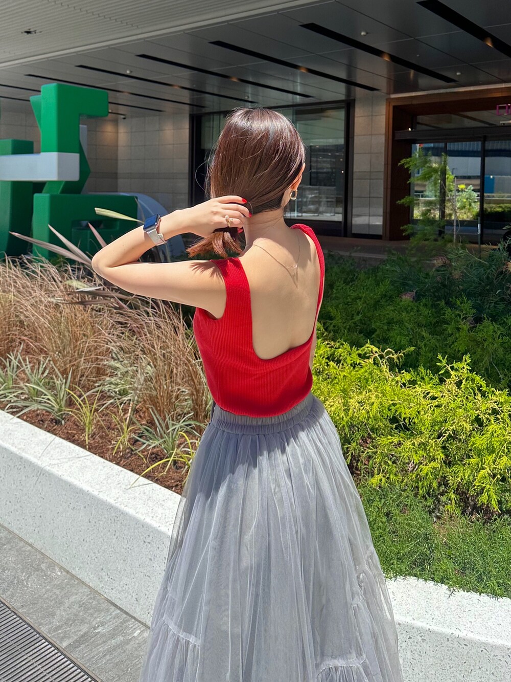 レッド系のタンクトップ、グレー系のスカートを着用したレディースの夏コーディネートの2枚目の写真