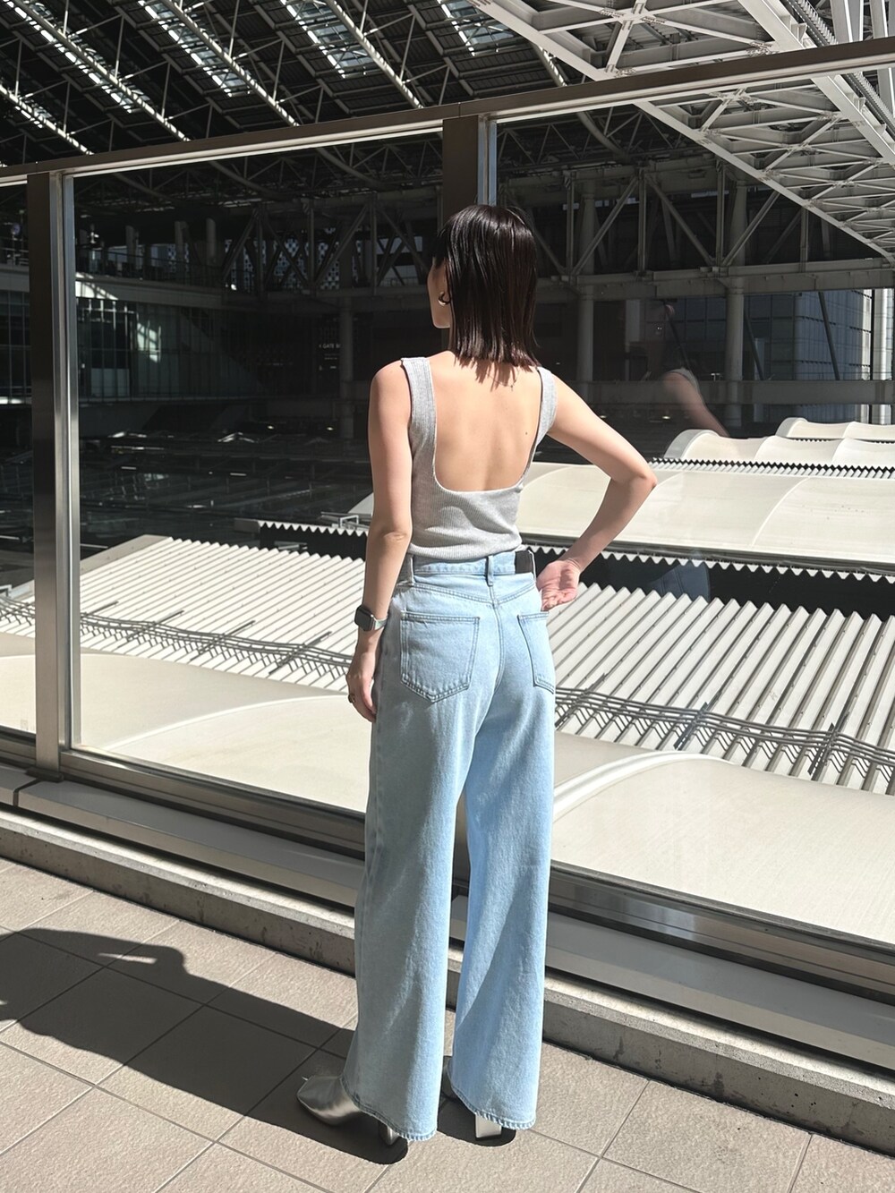 ブルー系のデニムパンツ、シルバー系のパンプス、グレー系のタンクトップを着用したレディースの春コーディネートの6枚目の写真