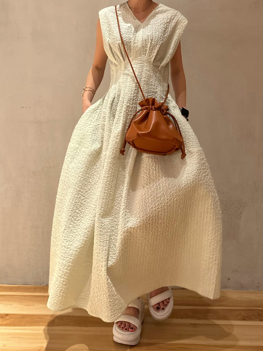 ベージュ系のテーラードジャケット、グリーン系のワンピース、ホワイト系のサンダルを着用したレディースの冬コーディネートの5枚目の写真