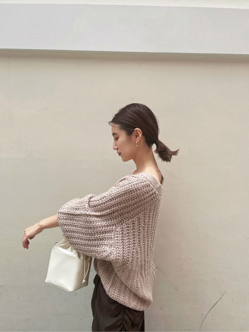 ブラック系のその他シューズ、ホワイト系のハンドバッグ、ブラウン系のスカートを着用したレディースの秋コーディネートの3枚目の写真