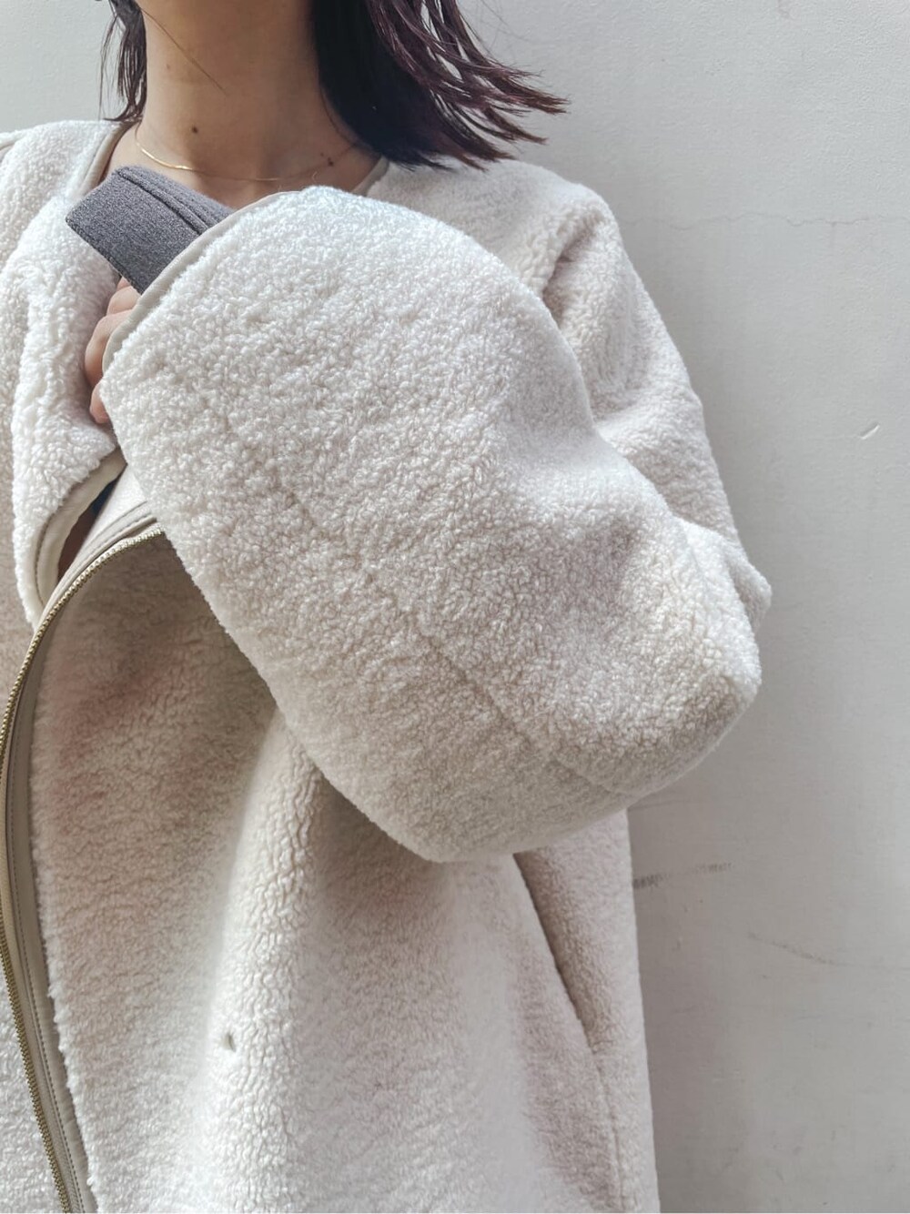 ブラック系のブーツ、ホワイト系のその他アウター、ベージュ系のワンピースを着用したレディースの秋コーディネートの9枚目の写真