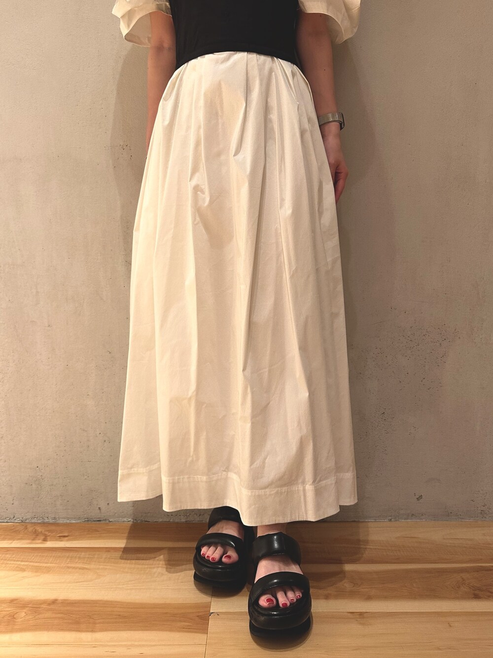 ブラック系のサンダル、ホワイト系のワンピース、ゴールド系のピアス（両耳用）を着用したレディースの夏コーディネートの4枚目の写真