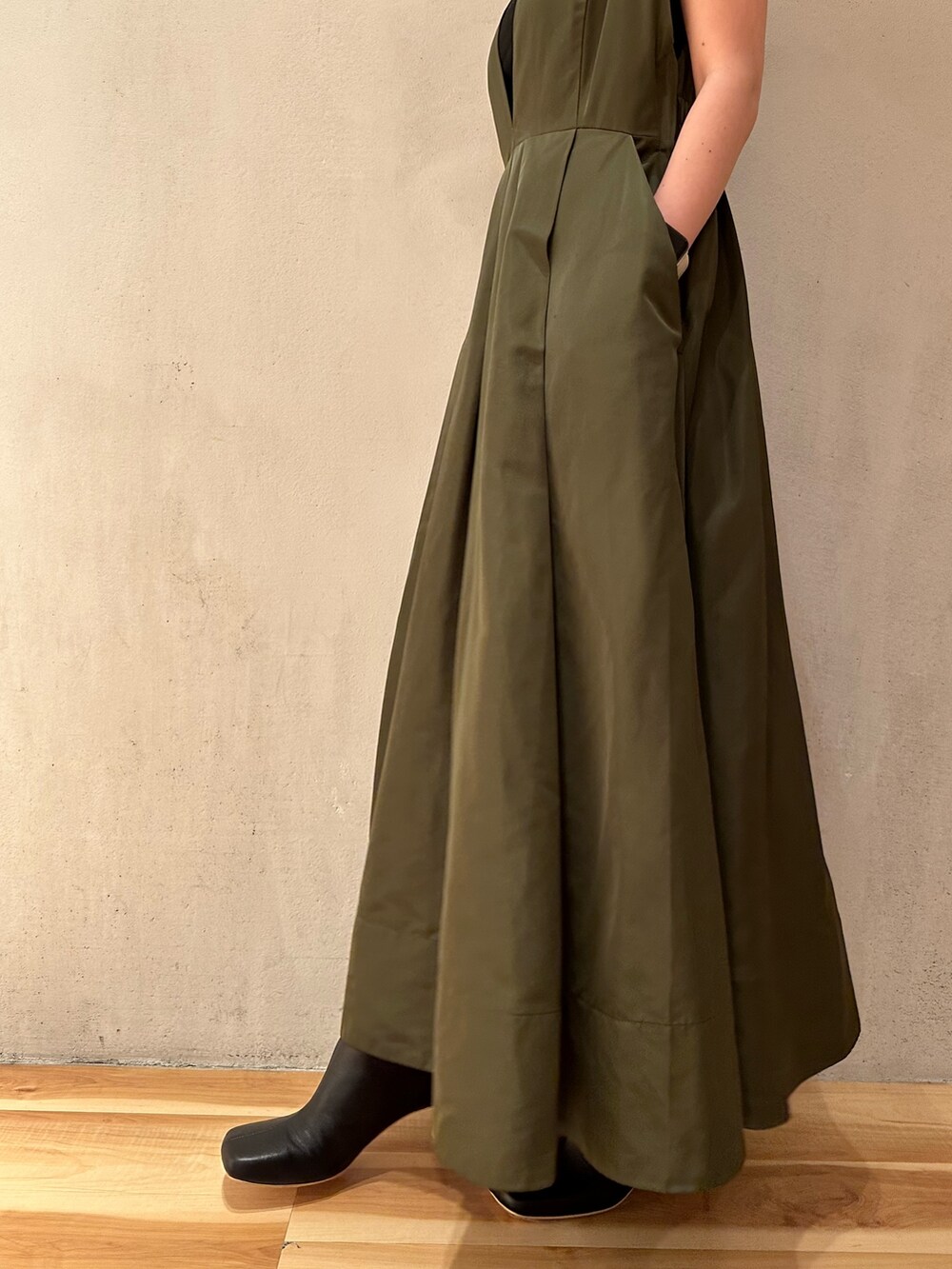 グリーン系のジャンパースカート、ブラック系のブーツを着用したレディースの夏コーディネートの6枚目の写真