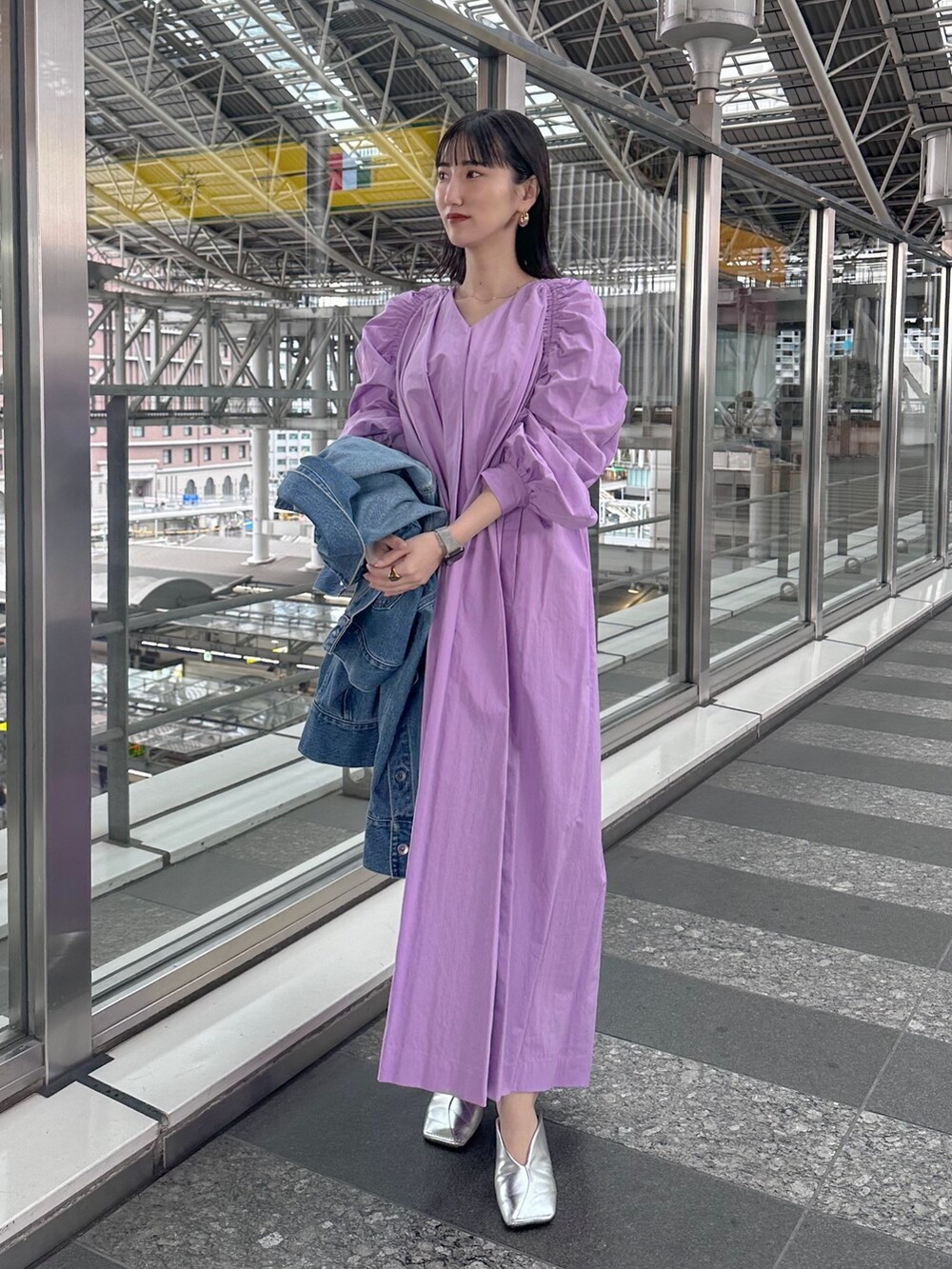 パープル系のワンピース、ブルー系のデニムジャケット、シルバー系のパンプスを着用したレディースの春コーディネートの2枚目の写真