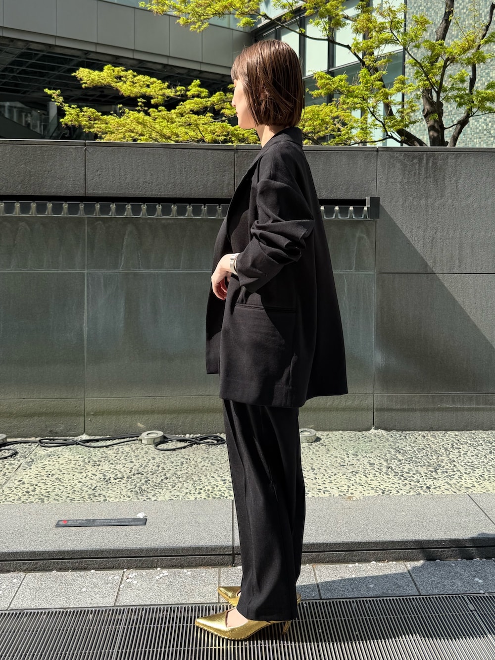 ブラック系のテーラードジャケット、ブラック系のその他パンツ、ゴールド系のサンダルを着用したレディースの春コーディネートの3枚目の写真