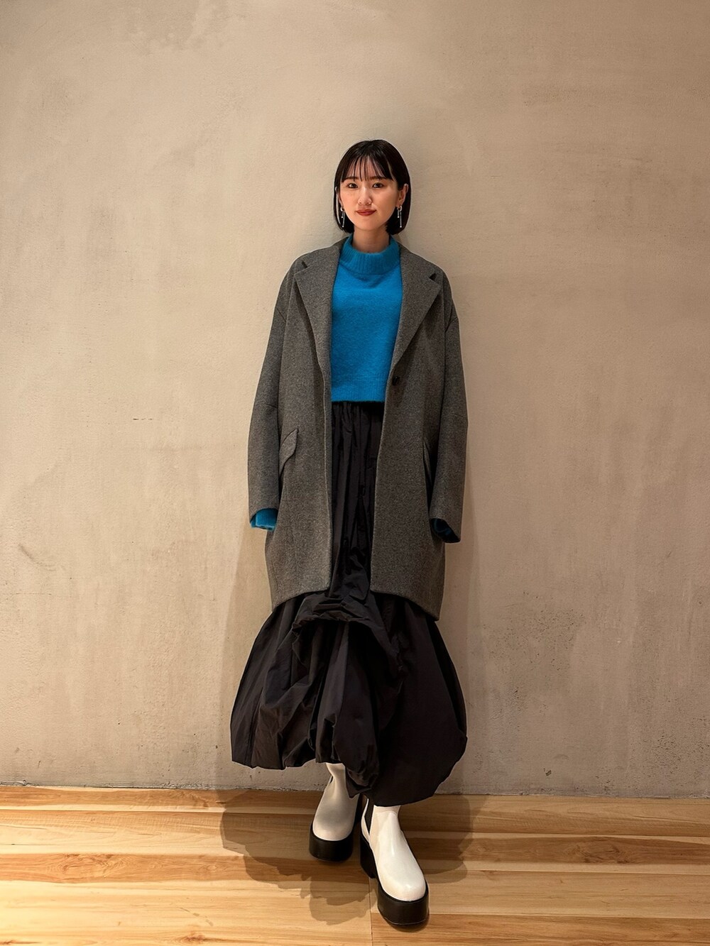 ブラック系のスカート、ブルー系のニット/セーター、ホワイト系のブーツを着用したレディースの冬コーディネートの8枚目の写真