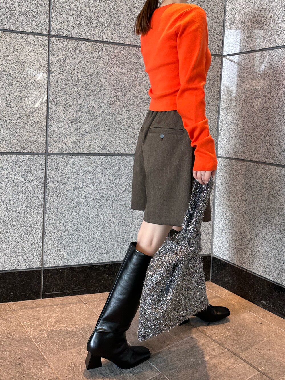オレンジ系のニット/セーター、ブラウン系のテーラードジャケット、ブラウン系のスカートを着用したレディースの秋コーディネートの7枚目の写真