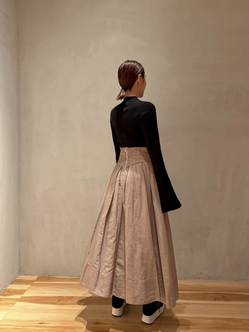 ブラック系のニット/セーター、ベージュ系のスカート、ブラック系のスニーカーを着用したレディースの冬コーディネートの3枚目の写真