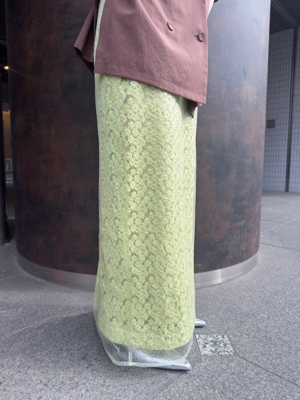 シルバー系のパンプス、ブラウン系のテーラードジャケット、グリーン系のスカートを着用したレディースの春コーディネートの8枚目の写真