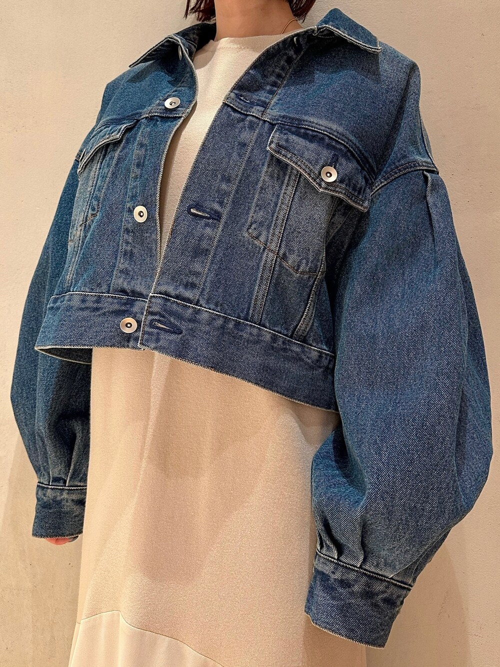 ブルー系のデニムジャケット、ベージュ系のワンピース、ホワイト系のスニーカーを着用したレディースの春コーディネートの4枚目の写真