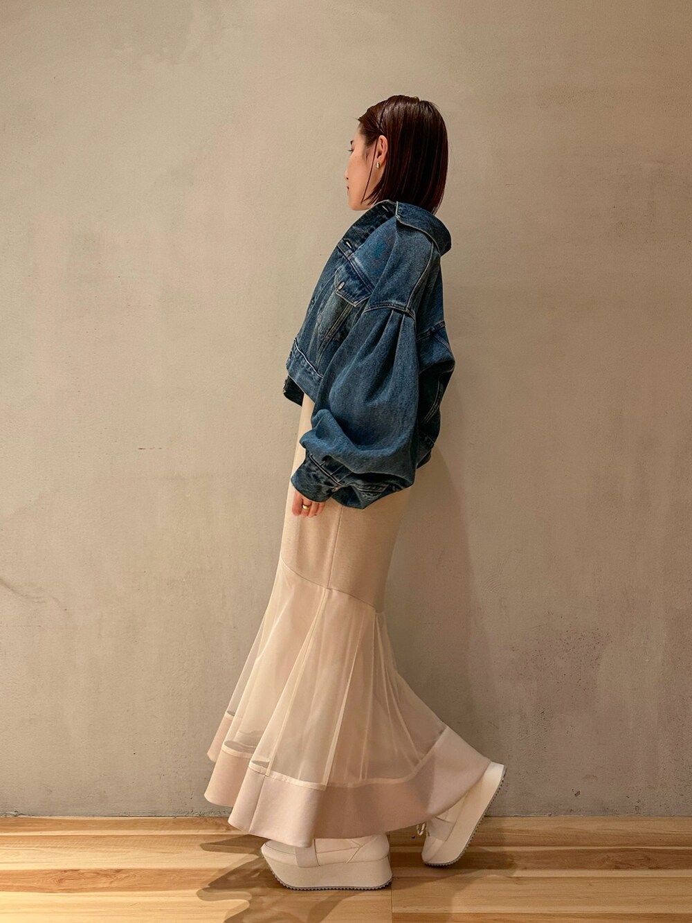 ブルー系のデニムジャケット、ベージュ系のワンピース、ホワイト系のスニーカーを着用したレディースの春コーディネートの2枚目の写真