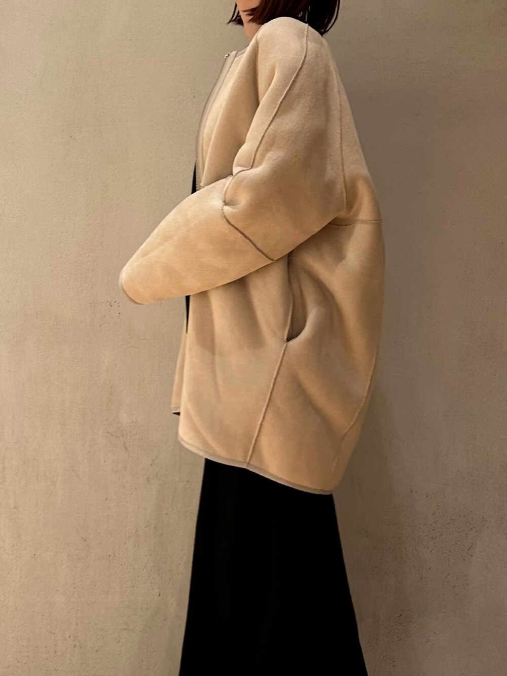 ブラック系のスカート、ブラック系のブーツ、ベージュ系のノーカラーコートを着用したレディースの夏コーディネートの6枚目の写真