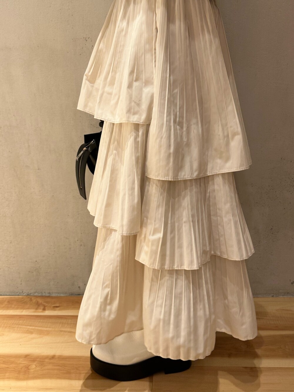 ホワイト系のスカート、ブルー系のニット/セーター、ベージュ系のノーカラーコートを着用したレディースの秋コーディネートの5枚目の写真